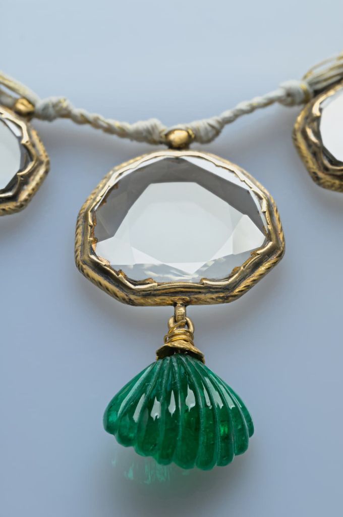 The central table-cut diamond of the necklace with its carved emerald shell pendant.