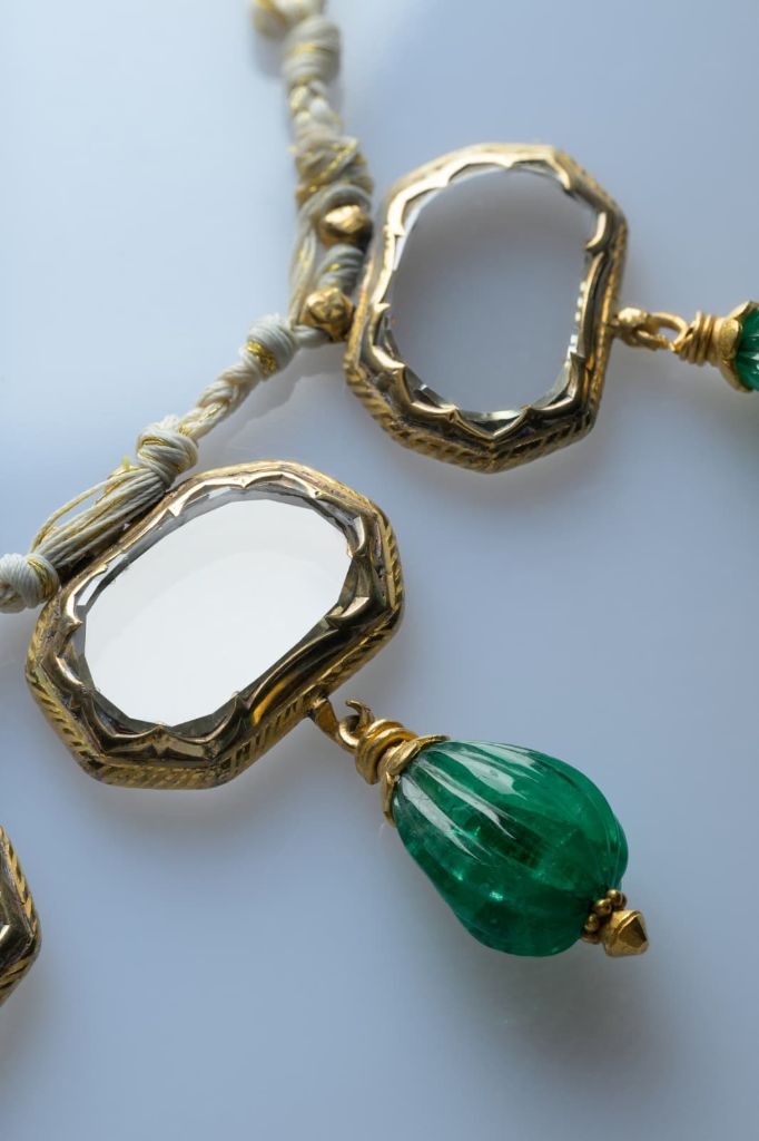 Two gold and white-enamel frames, each holding a flat table-cut diamond.